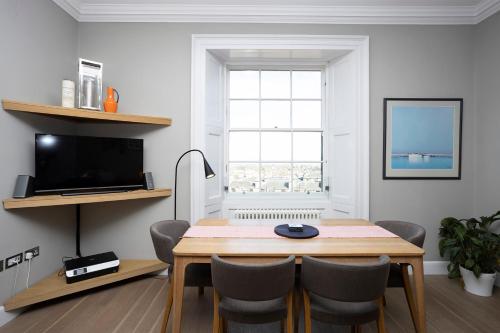 a dining room with a table and chairs and a television at JOIVY Splendid Apartment in New Town in Edinburgh