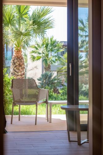 a chair sitting on a porch with a palm tree at Almyros Beach in Acharavi