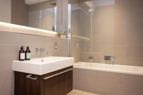 a bathroom with a white sink and a bath tub at JOIVY Splendid Apartment in New Town in Edinburgh
