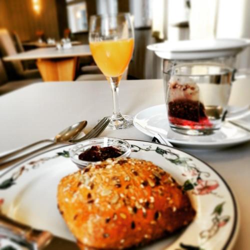 a table with a plate of food and a glass of orange juice at Lindner's Hotel in Bellheim