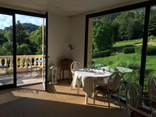 a dining room with a table and a view of a garden at Domaine Du Moulin Vallée Heureuse in Poligny