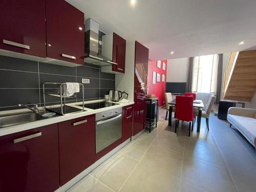 une cuisine avec des placards rouges et une salle à manger dans l'établissement Les Logis des Vignobles Sainte Emilion en Duplex n 1 avec terrasse, à Saint-Émilion
