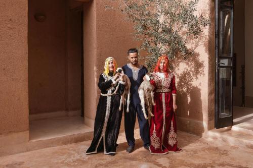a man and two women standing next to a wall at Tagadert Lodge in Oumnas