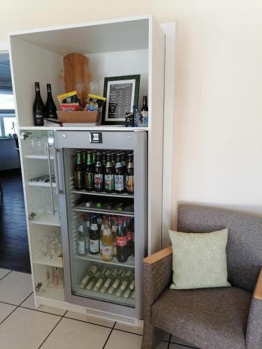 a refrigerator filled with lots of drinks next to a couch at Lindner's Hotel in Bellheim