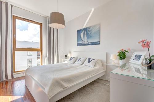 a white bedroom with a bed and a window at Dom & House - Apartamenty Nadmorski Dwór in Gdańsk