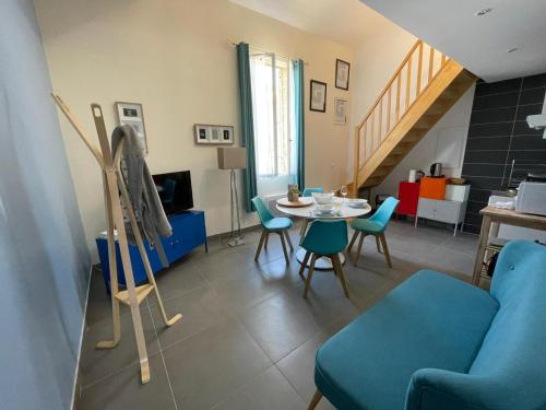 un salon avec un canapé bleu, une table et des chaises dans l'établissement Les logis des Vignobles Saint Emilion en Duplex n 2 avec terrasse, à Saint-Émilion