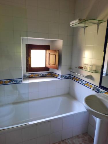 baño con bañera, lavabo y ventana en Casa de Aldea Florentina en Arenas de Cabrales
