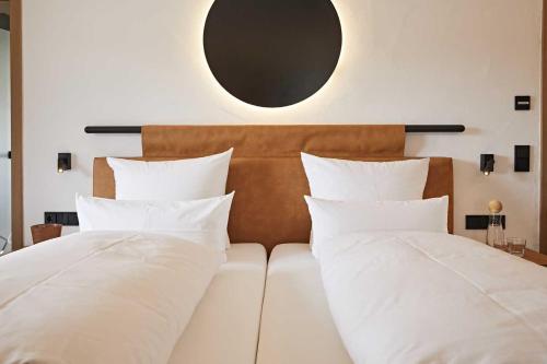 a bed with white pillows and a mirror on the wall at Hotel Rosenstock - Erwachsenenhotel - Adults only 15 plus in Fischen