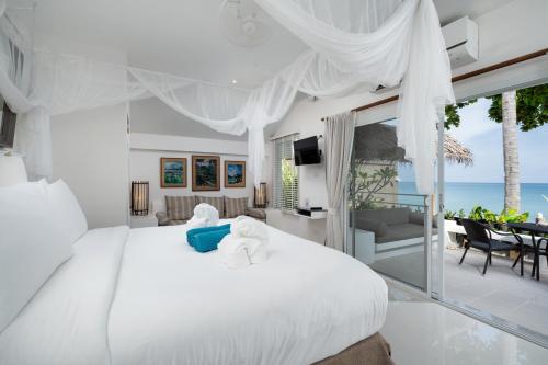 a bedroom with a white bed with a view of the ocean at King's Garden Resort - SHA Plus in Chaweng
