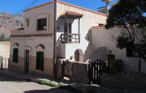 uma casa branca com uma cerca à frente. em La Quebrada Enigmática. Arte, mística e historia em Tilcara