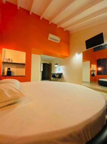 a bedroom with a white bed and an orange wall at Motel Ilha de Capri in São Bernardo do Campo