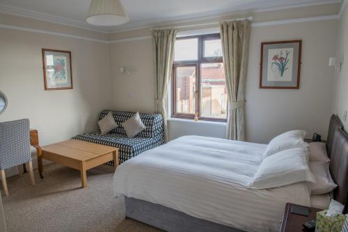 een slaapkamer met een bed, een stoel en een raam bij Toothbrush Rooms at Lattice Lodge - Self Catering & EV Recharging in Ipswich