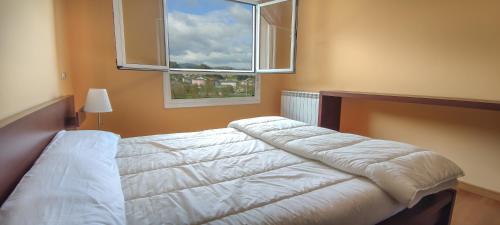 ein Schlafzimmer mit einem weißen Bett mit einem Fenster in der Unterkunft HOLIDAY HOMES by del abuelo VEGADEO in Vegadeo