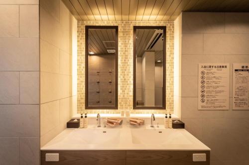 La salle de bains est pourvue d'un grand lavabo blanc et d'un miroir. dans l'établissement Super Hotel Hiroshima Yagenboridori, à Hiroshima