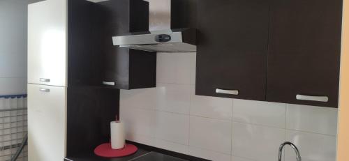 une cuisine avec des placards noirs et une bougie sur un tabouret rouge dans l'établissement INSIDEHOME Apartments - El Capricho de Elsa, à Unquera