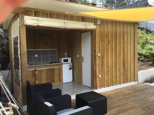 a backyard patio with an outdoor kitchen with chairs and an umbrella at Glamping Cabana nas arvores in Ponte da Barca