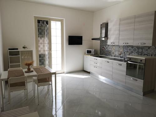 kuchnia z białymi szafkami i stołem z krzesłami w obiekcie Romano Appartamenti w Trapani