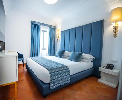 a bedroom with a large bed with blue accents at Hotel Oasi Di Kufra in Sabaudia