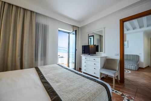 a bedroom with a bed and a television and a chair at Hotel Oasi Di Kufra in Sabaudia