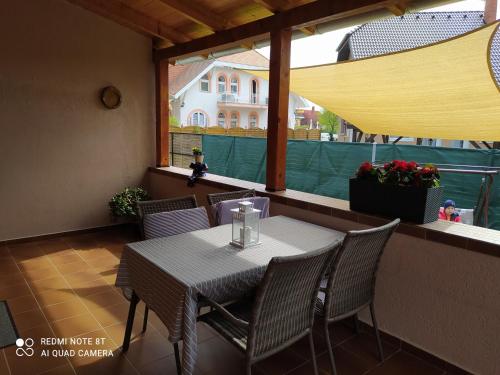 a table and chairs sitting on a balcony with a window at Forrás-G Vendégház in Bük
