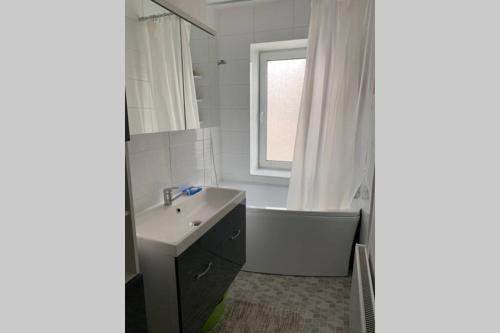 a bathroom with a sink and a bath tub and a window at Skolas street seaside space! in Jūrmala