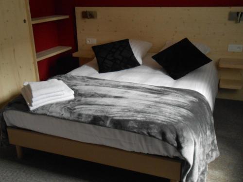 a bed with white sheets and black pillows at Gite Ungersberg in Itterswiller