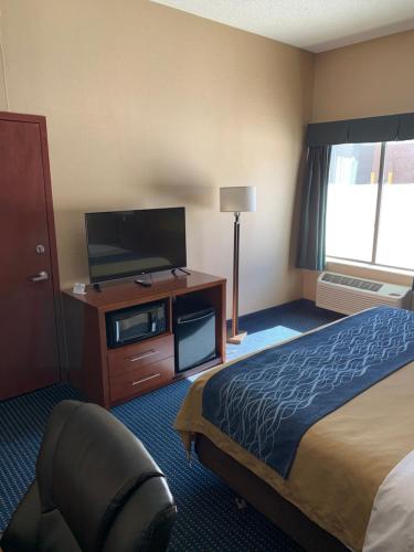 a hotel room with a bed and a flat screen tv at Comfort Inn Crystal Lake - Algonquin in Crystal Lake