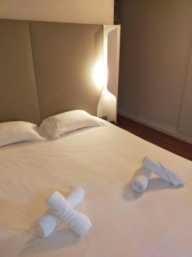 two rolls of towels on a white bed at The Originals Access, Hôtel Foix in Foix
