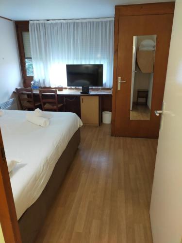 a bedroom with a bed and a desk with a television at The Originals Access, Hôtel Foix in Foix