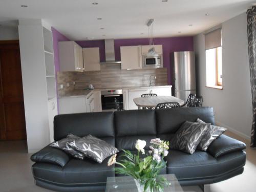 a living room with a black couch and a kitchen at Gite Ungersberg in Itterswiller
