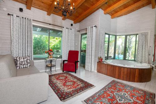 uma sala de estar com uma banheira e uma cadeira vermelha em Marom Romance em Kahal