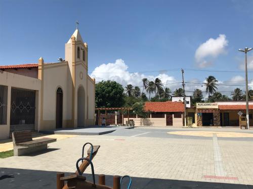 a church with a clock tower next to a street at Os Navegantes B in Guajiru