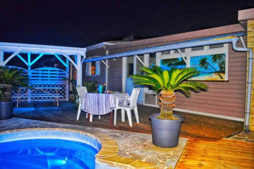 a house with a pool and a table and chairs at Les Bungalows Couleurs Soleil in Le Vauclin