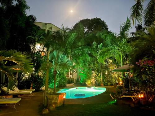 a swimming pool with palm trees around it at night at Casa Da Praia in Candolim