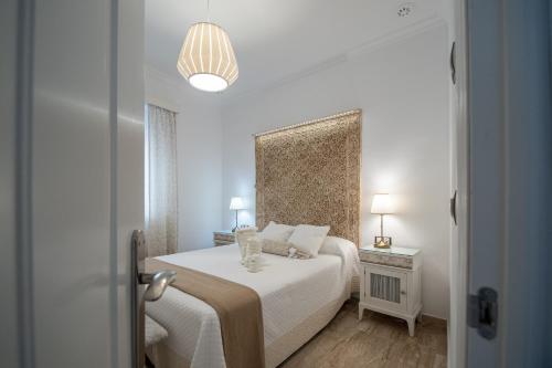 een witte slaapkamer met een bed en een lamp bij Apartamento Garum in Cádiz