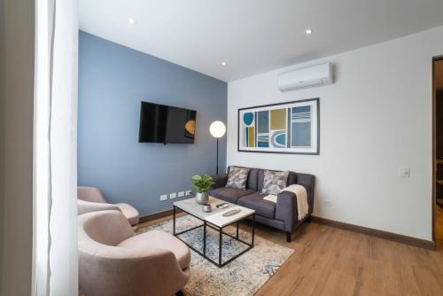 a living room with blue walls and a couch and chairs at Cali River Suites by Yellowkey Capital in Cali