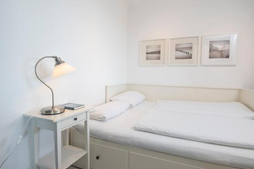 un letto bianco con lampada su un comodino di Haus Meeresgruß Sunshine a Grömitz