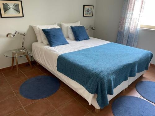 a bedroom with a large bed with blue sheets and pillows at Casa na Praia Meco - Villas Vale do Meco in Alfarim