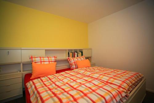 a bedroom with a bed with orange pillows at Ferienwohnung SEE - ZEIT in Immenstaad am Bodensee