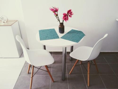 einen weißen Tisch mit zwei Stühlen und eine Vase mit Blumen in der Unterkunft Studio Centrum - 1 Maja 16 in Zabrze