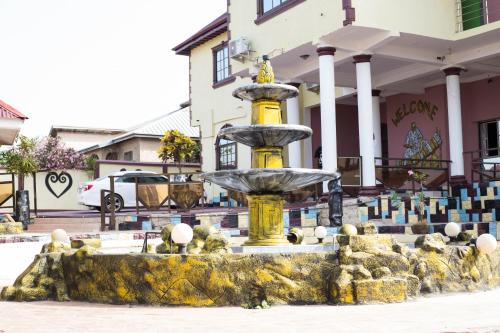a yellow fountain in front of a building at Gya-son Royal Guest House in Kumasi
