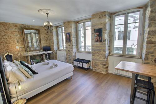 a bedroom with a bed and a table and windows at Appartement centre-ville CHIC in Vannes