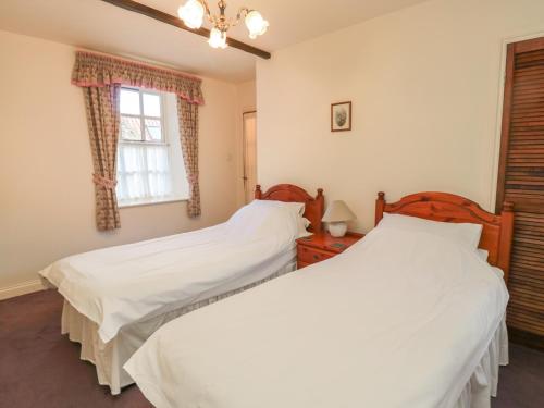 two beds in a bedroom with a window at Bracken Lodge in Wooler