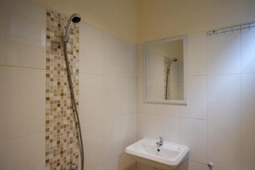 ein weißes Badezimmer mit Waschbecken und Dusche in der Unterkunft RedDoorz near Ambarrukmo Plaza Mall in Yogyakarta