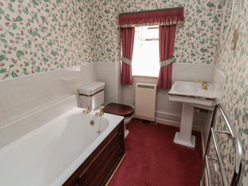 a bathroom with a bath tub and a sink at Rose Cottage in Wooler