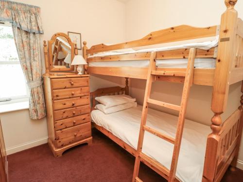 a bedroom with two bunk beds and a dresser at Fern Cottage in Wooler