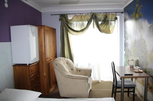 a room with a chair and a table and a window at Pensjonacik ELMI in Giżycko