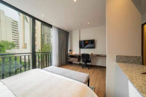 a hotel room with a balcony with a bed and a desk at Cali River Suites by Yellowkey Capital in Cali