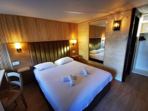 1 dormitorio con 1 cama blanca grande y toallas. en The Originals Access, Hôtel Foix (P'tit Dej-Hotel), en Foix