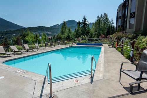 a large swimming pool with chairs and a building at The Ironwood on Blueberry Hill in Whistler